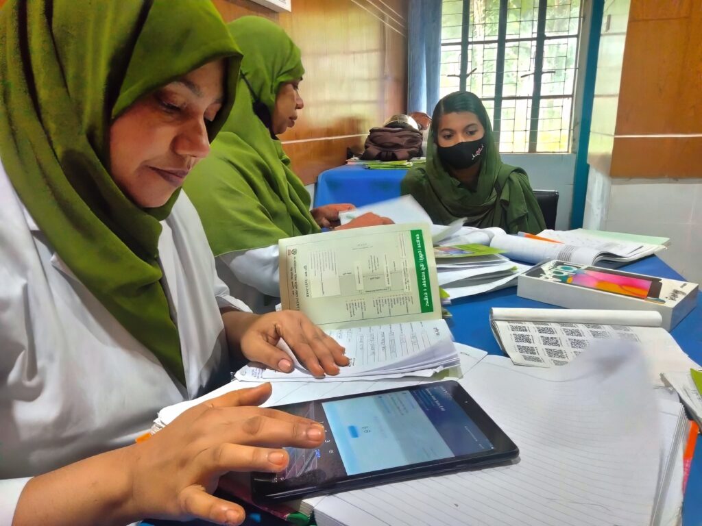 Two heathcare workers recording a patients blood pressure in the Simple app on a tablet.